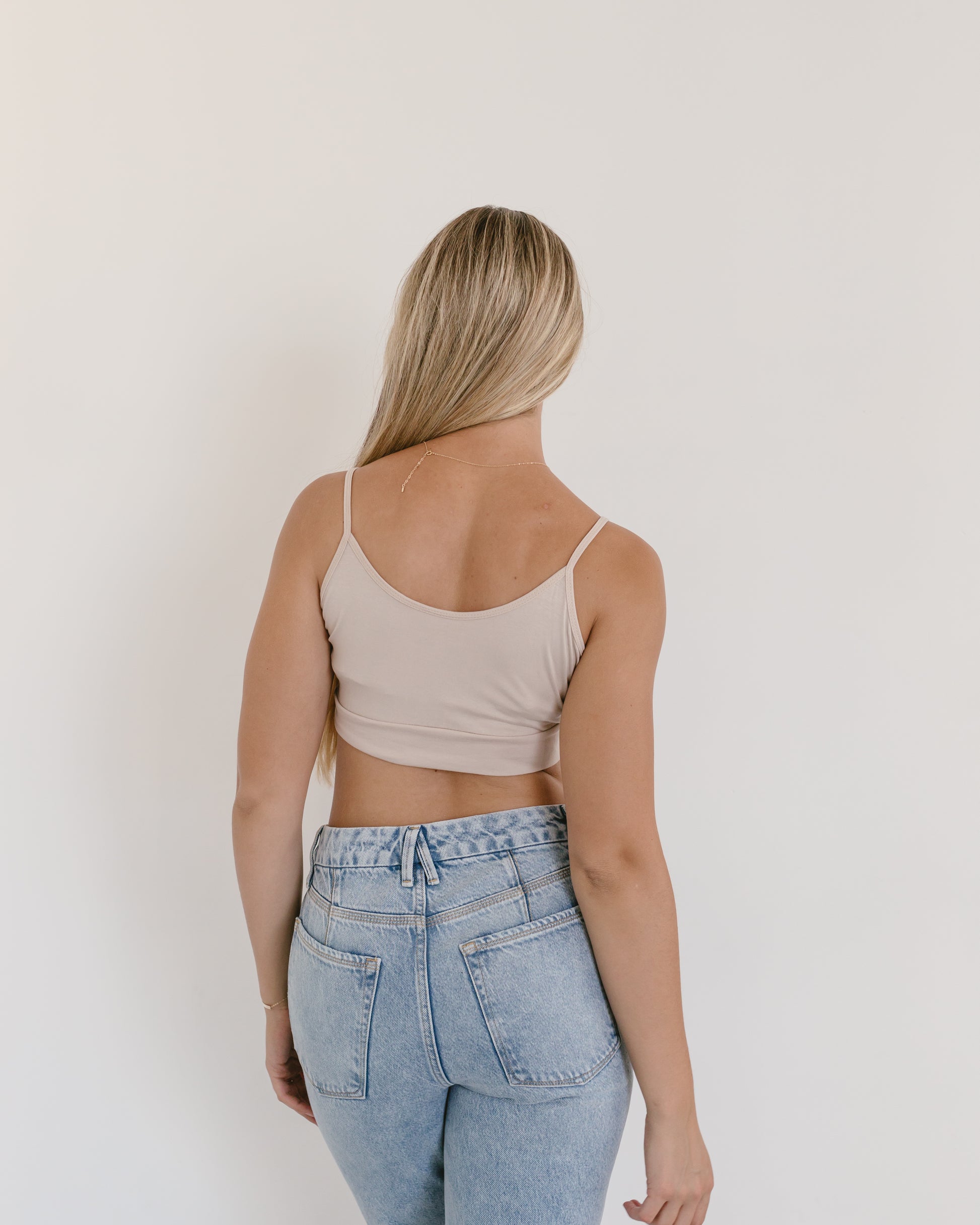 Woman in jeans and black crop top, wearing white Spaghetti Strap Halftee.