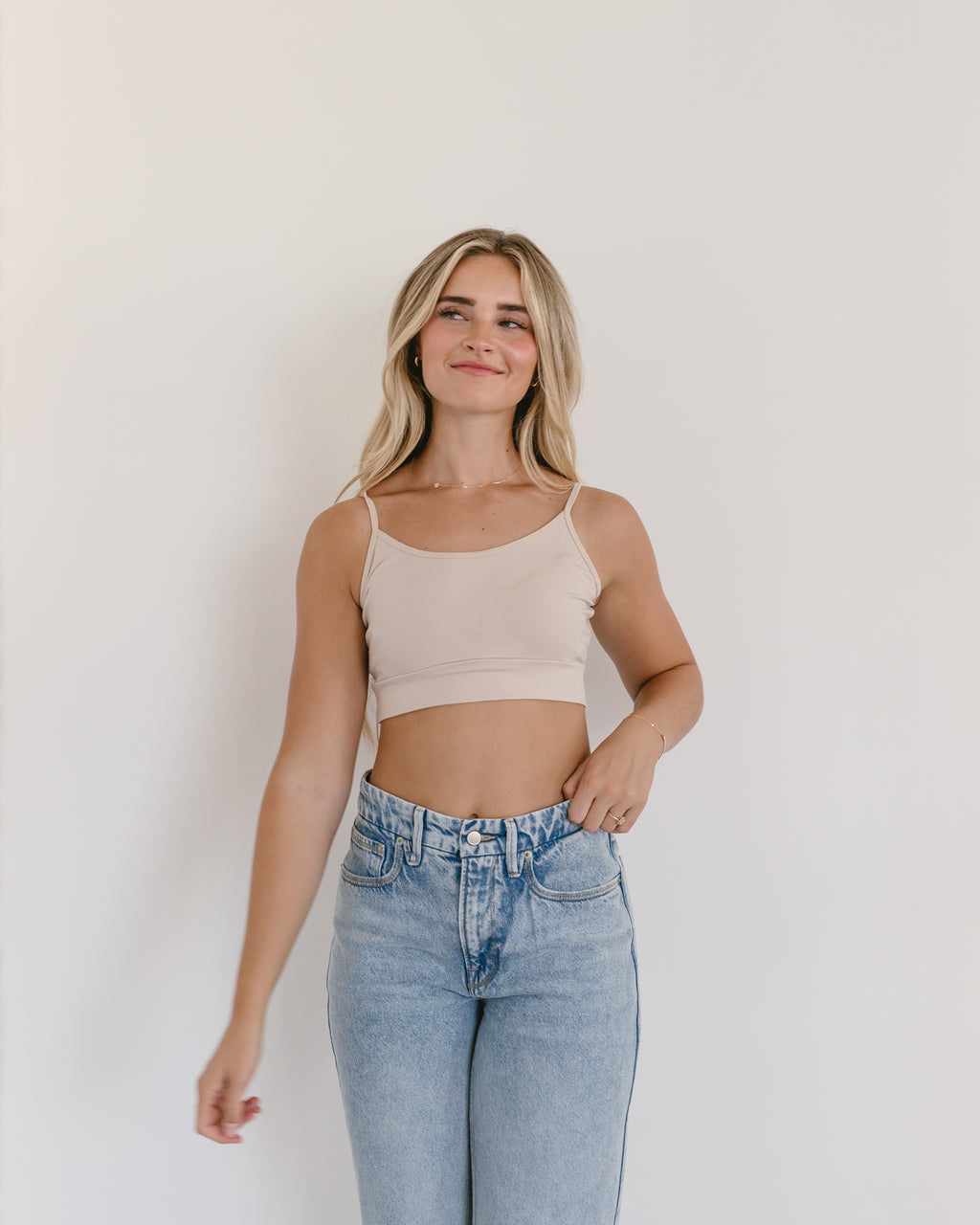 Woman in jeans and black crop top, wearing white Spaghetti Strap Halftee.