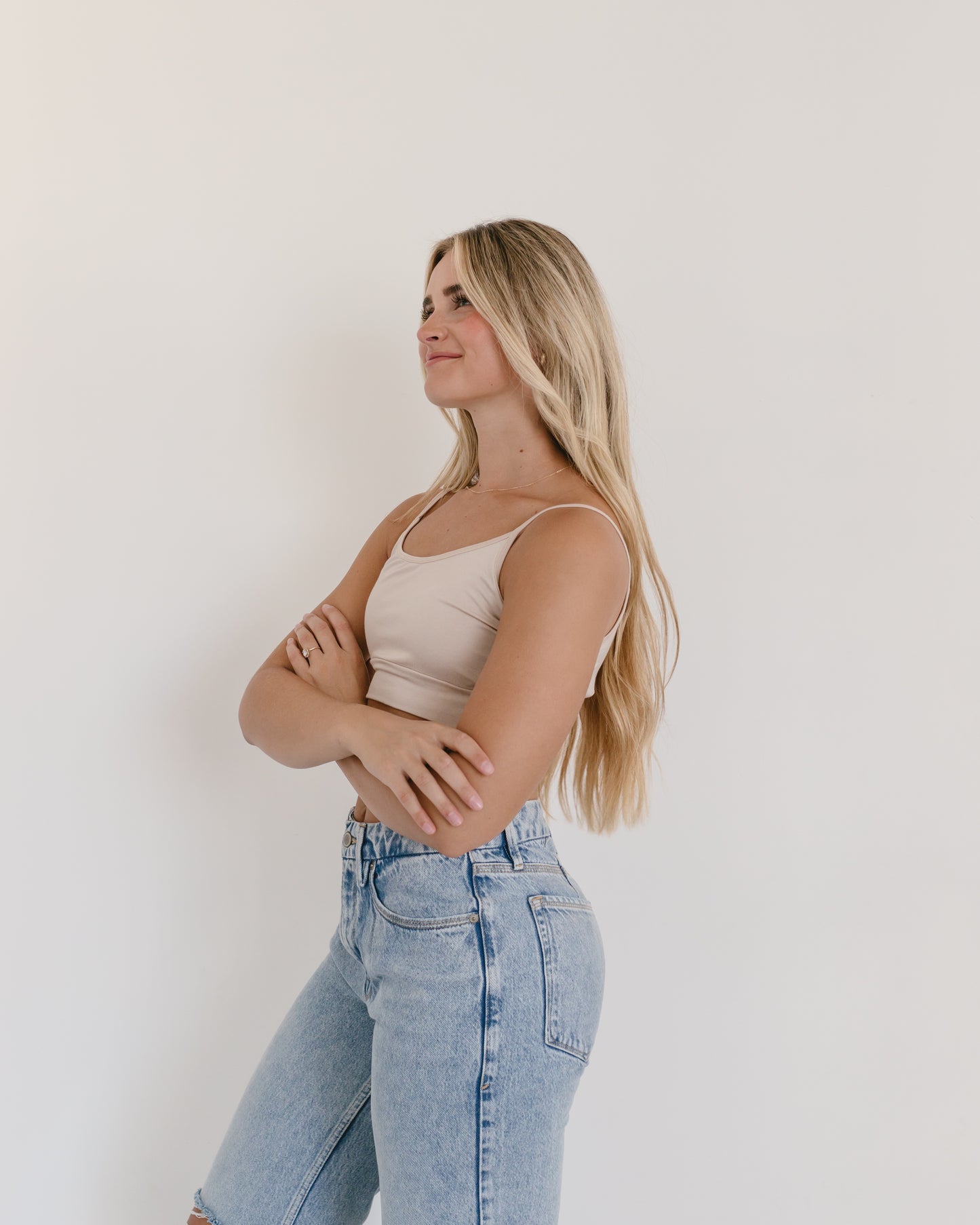 Woman in jeans and black crop top, wearing white Spaghetti Strap Halftee.