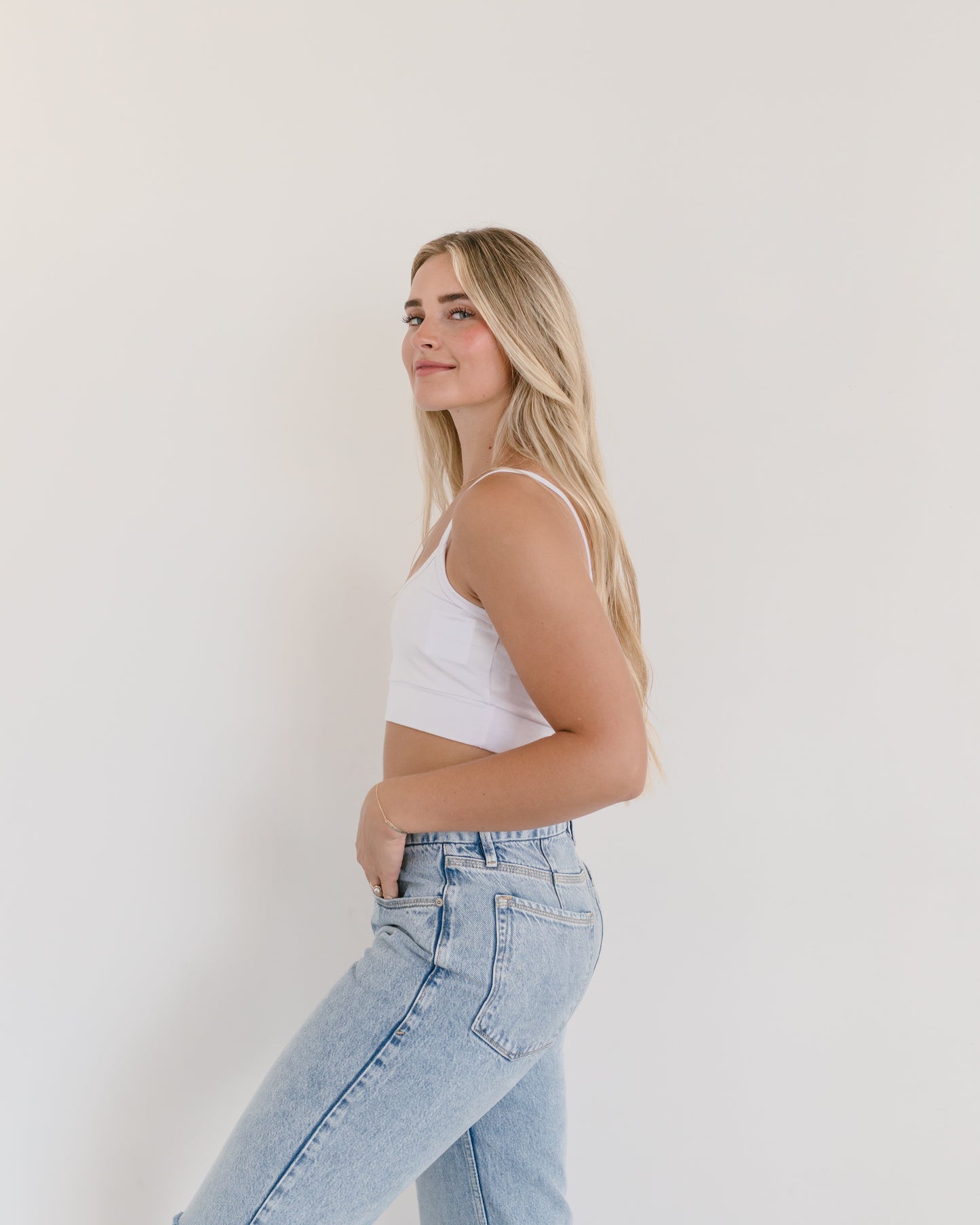 Woman in jeans and black crop top, wearing white Spaghetti Strap Halftee.