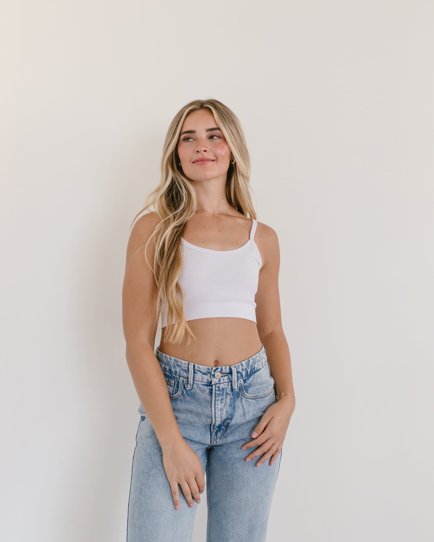 Woman in jeans and black crop top, wearing white Spaghetti Strap Halftee.