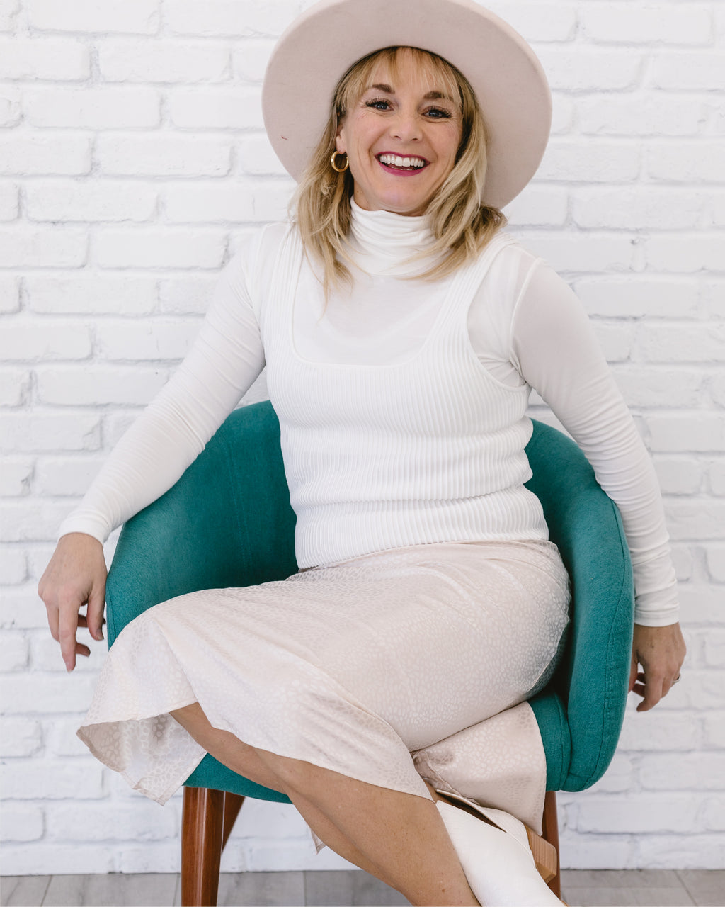  Woman in white sweater and hat sitting on green chair, wearing Midi Animal Print Skirt.
